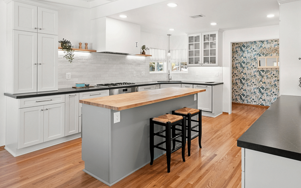 White kitchen with a central island with two stools.