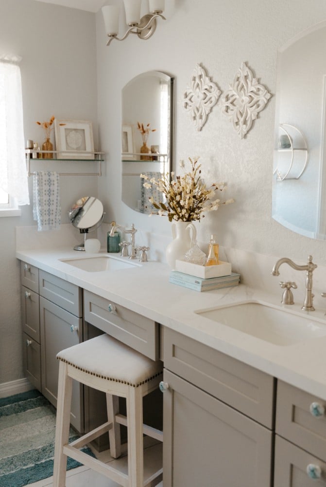 Cozy San Diego bathroom remodel with gray double vanity, soft decor, and built-in makeup station.