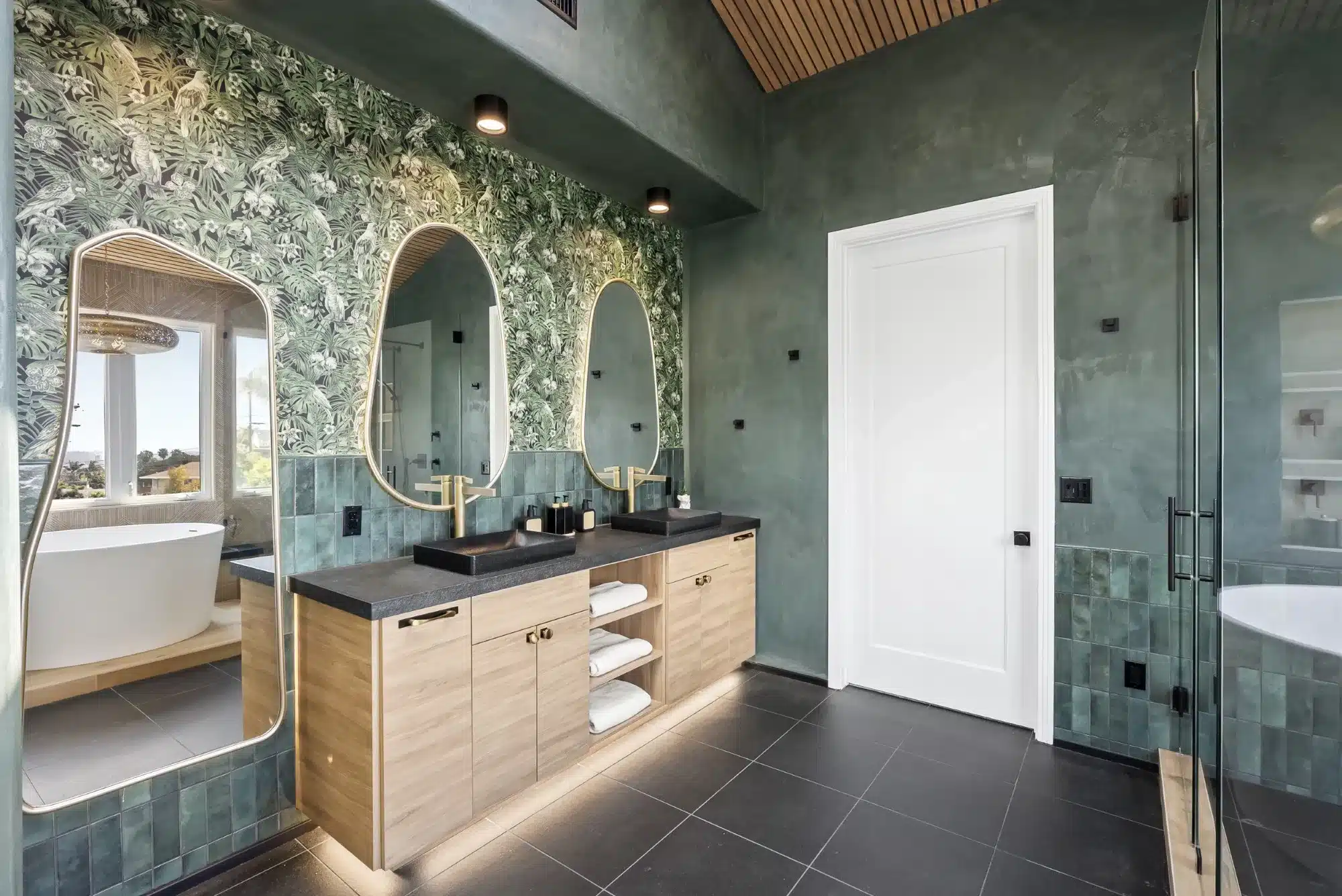 Modern San Diego bathroom remodel with green plaster walls, tropical wallpaper, and floating double vanity.