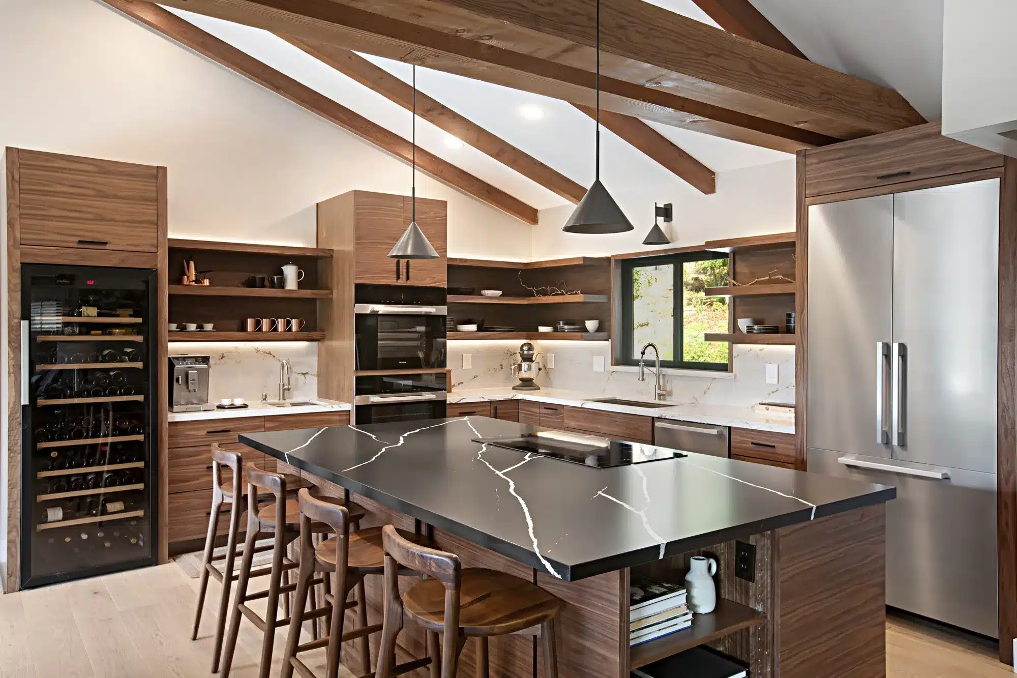 Contemporary kitchen with wood cabinetry, black stone island, and vaulted ceiling with exposed beams
