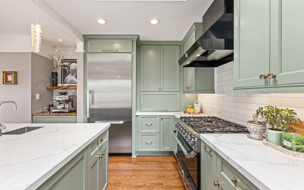 Elegant kitchen remodel with sage green cabinets, marble countertops, and stainless steel appliances